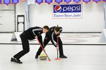 The Reds Evan MacKnight and Trevor Crouse sweep a rock during play at the Subway AUS Curling Championships, in St. John's. (Photo: Dani Ahmed/for Memorial Athletics)